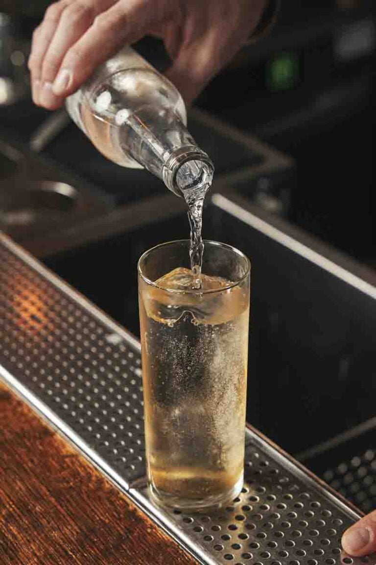 Photo d'un homme en train de servir une eau pétillante dans un verre.