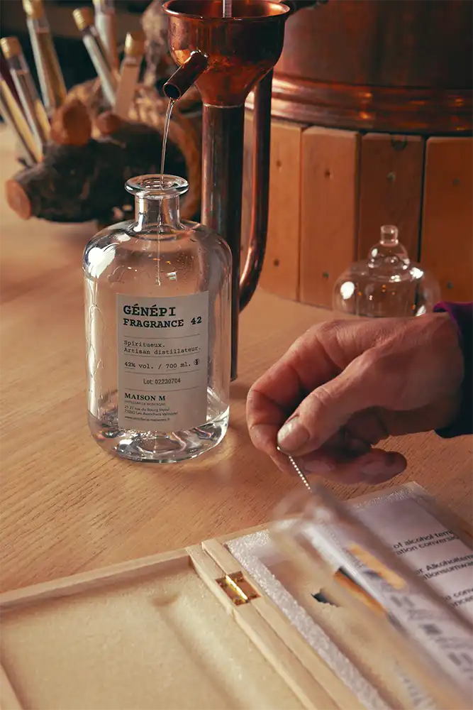 Photo de distillation de génépi sortant de l'alambic en cuivre dans la distillerie Maison M.
