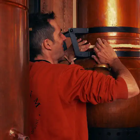 Photo d’un homme dans une distillerie en train de tenir un alambic