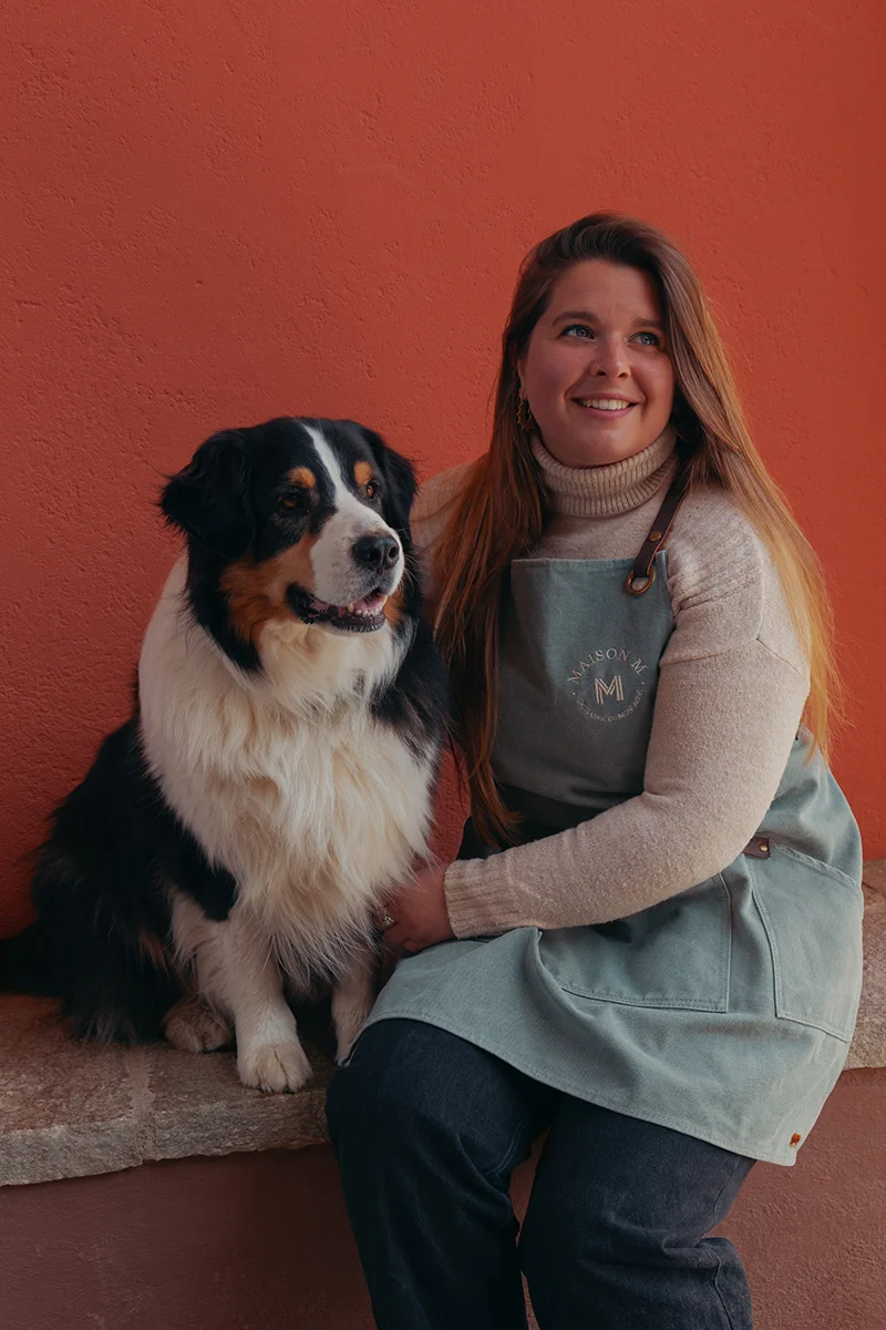 Photo de Julia Deloménie avec son chien devant la distillerie Maison M.