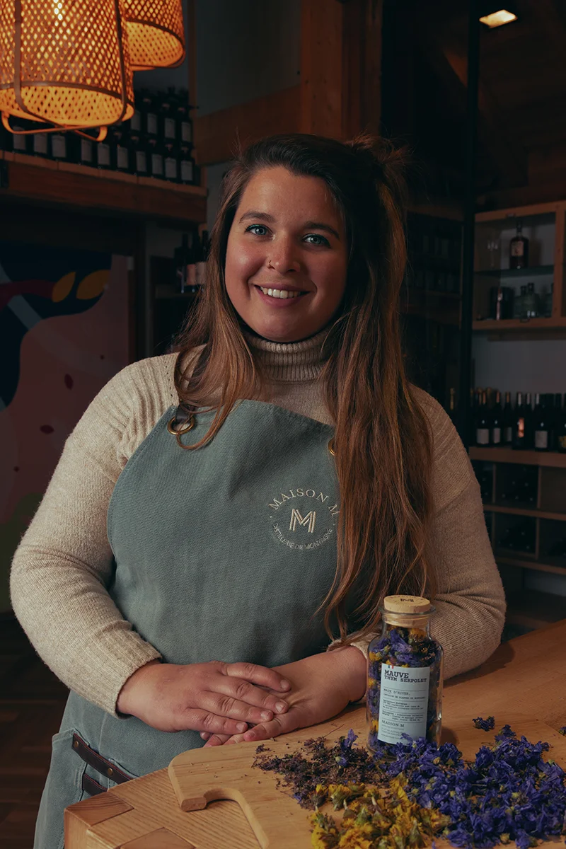 Photo de Julia Deloménie dans la distillerie Maison M avec devant elle une infusion à la mauve.