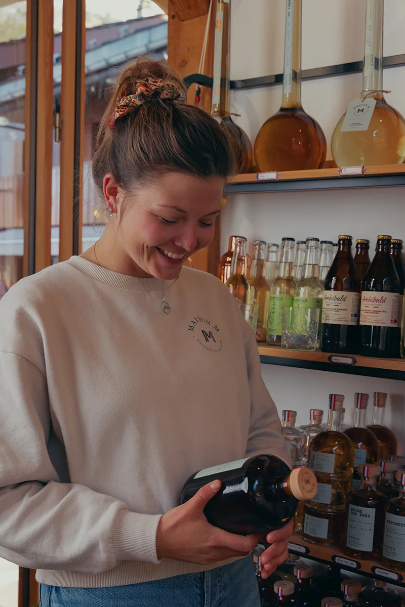 Photo de Fanny Harlin dans la distillerie Maison M tenant une bouteille.